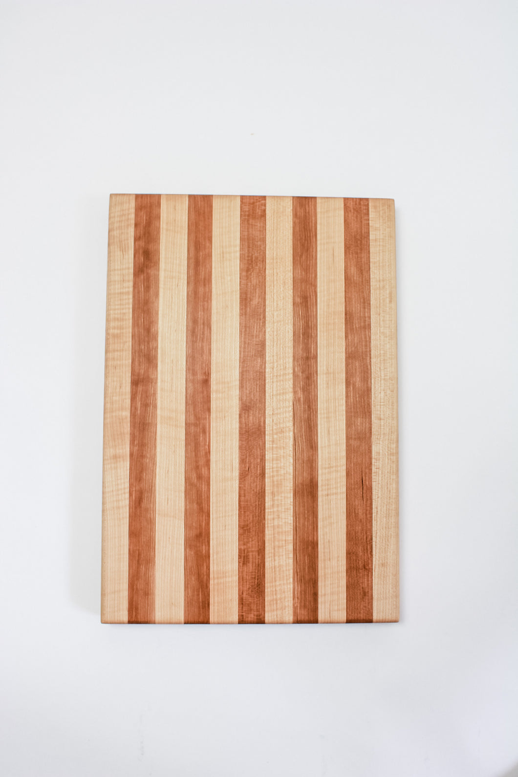 Handmade cutting board with alternating strips of cherry and hard maple wood.