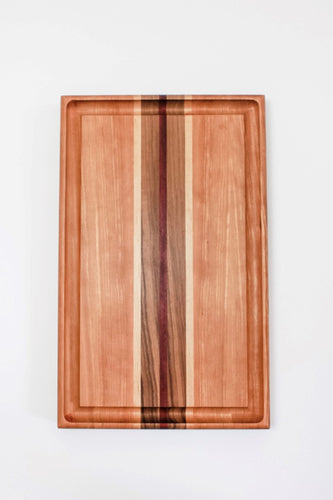 Cutting board made with cherry wood and strips of purpleheart, walnut and maple wood. This board features a juice groove.