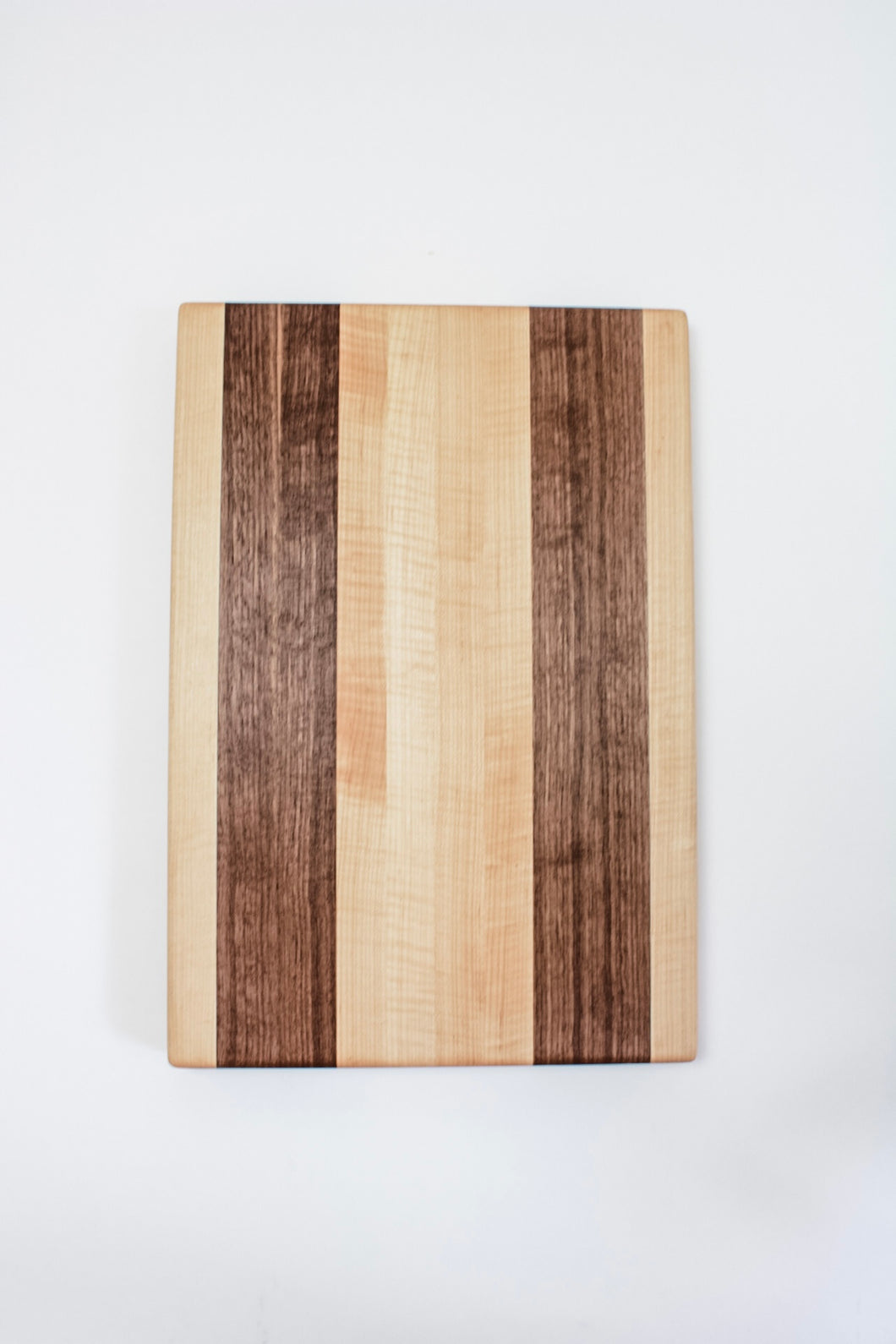 Handmade cutting board with alternating strips of walnut and hard maple wood.